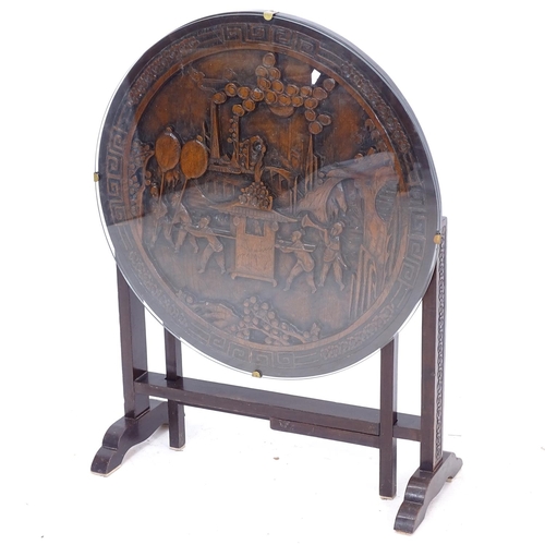 2252 - An Oriental hardwood circular-top folding table, the top having an inset 3-D relief carved panel, W6... 