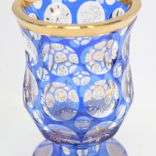 172 - A heavy Bohemian flashed blue overlay glass goblet, gilded instrument and floral decoration, with gi... 