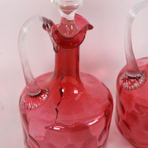 221 - A pair of cranberry glass decanters and stoppers, height 25cm (1 cracked)