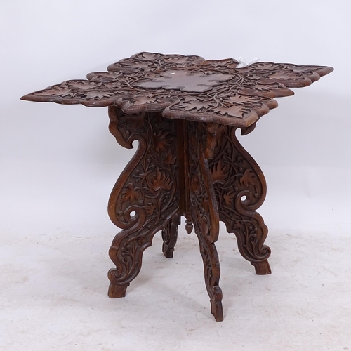 2328 - An Anglo-Indian hardwood occasional table, having a relief carved shaped top, on a 4-leg folding bas... 