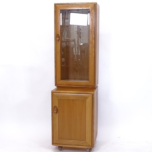 2213 - An Ercol light elm narrow display cabinet with cupboard base, W43cm