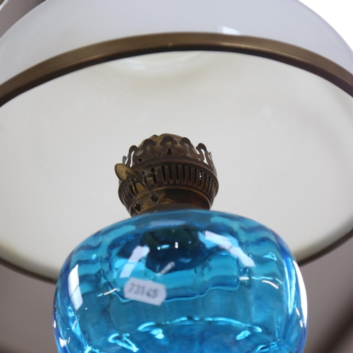 497 - A hanging glass oil lamp with brass mounts, having a blue font and milk glass shade, diameter overal... 