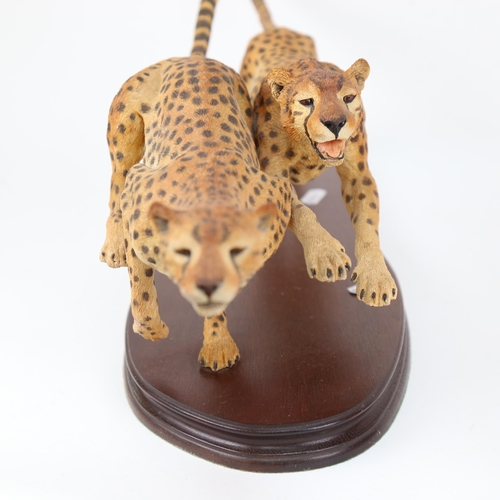 569 - A composition pair of bounding cheetahs, on wooden plinth, by Parker-Hale, length 52cm overall