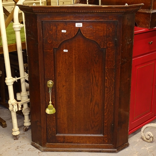 2593 - A George III oak hanging corner cabinet, with single panelled door