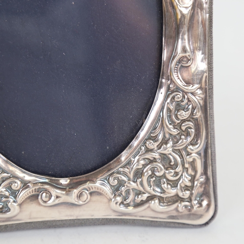 1071 - An Elizabeth II silver-fronted strut photo frame, relief embossed foliate decoration, with oval aper... 