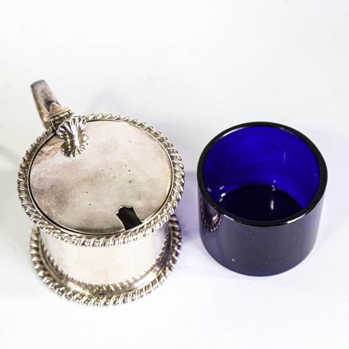 142 - A late Victorian silver drum-shaped mustard pot, with cast gadrooned rims and blue glass liner with ... 