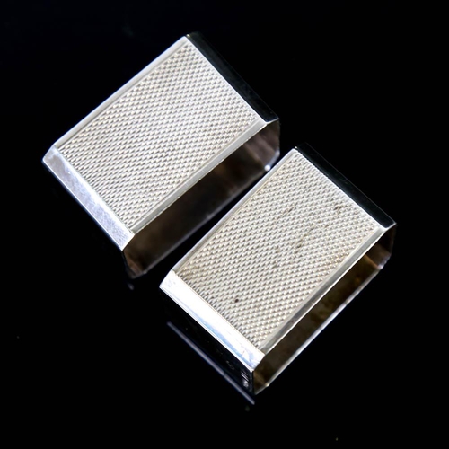 145 - A pair of Art Deco style Elizabeth II silver napkin rings, canted rectangular form with engine turne... 