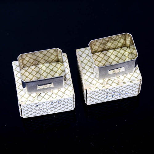 145 - A pair of Art Deco style Elizabeth II silver napkin rings, canted rectangular form with engine turne... 