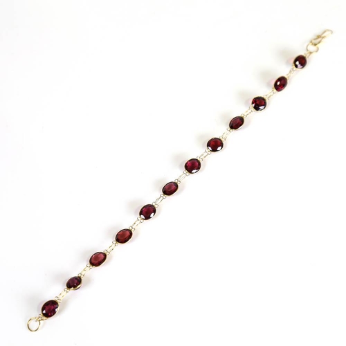 398 - A modern handmade 14ct gold garnet line bracelet, set with oval mixed cut garnets, bracelet length 1... 