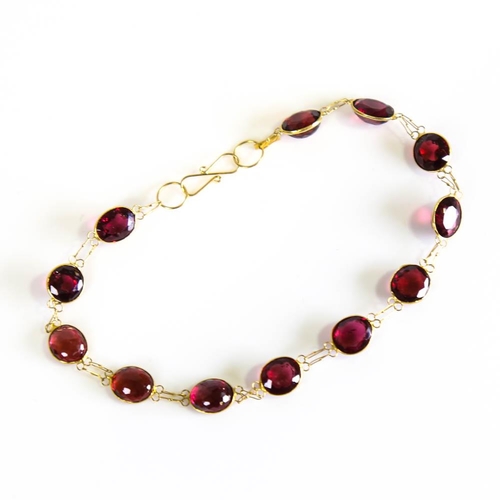 398 - A modern handmade 14ct gold garnet line bracelet, set with oval mixed cut garnets, bracelet length 1... 