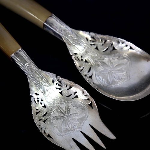 449 - A pair of Middle Eastern unmarked white metal horn-handled salad servers, engraved floral decoration... 