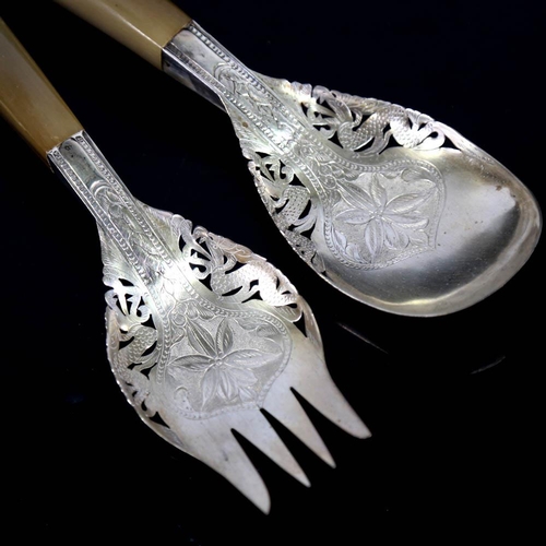 449 - A pair of Middle Eastern unmarked white metal horn-handled salad servers, engraved floral decoration... 