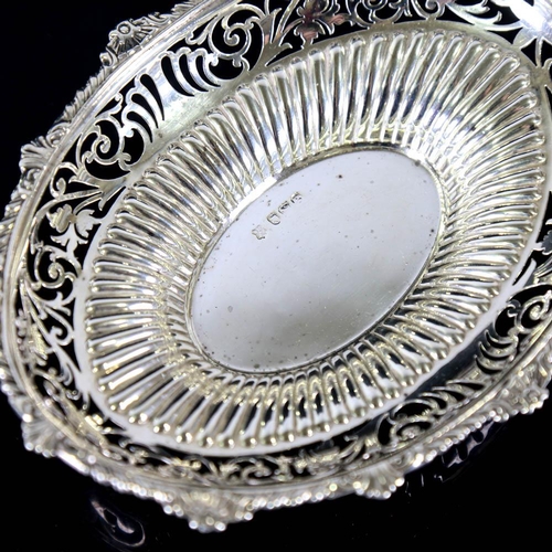 634 - An Edwardian silver bon bon dish, oval form with gadrooned rim, pierced foliate border and fluted de... 