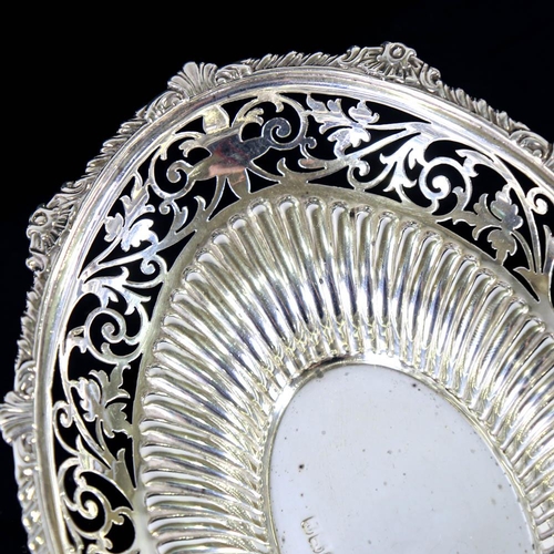 634 - An Edwardian silver bon bon dish, oval form with gadrooned rim, pierced foliate border and fluted de... 