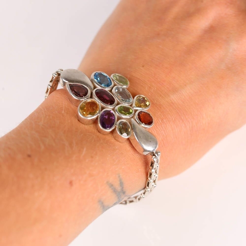 655 - A modern handmade silver gem-set bracelet, gemstones include blue topaz, garnet, amethyst, peridot, ... 