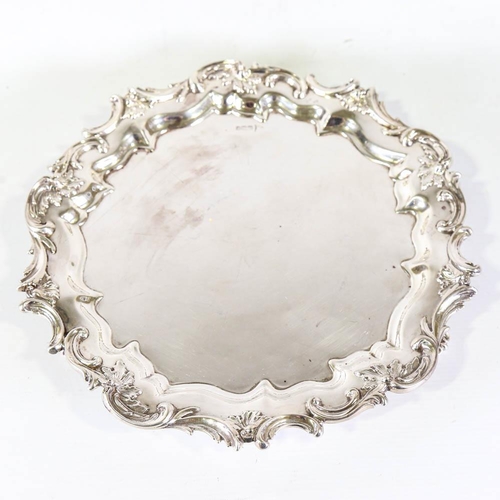 673 - A large Edwardian silver salver, circular form with cast foliate rim and scalloped inset border on t... 