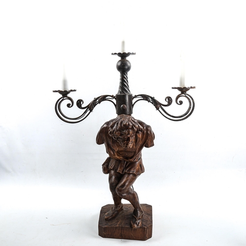 1011 - An unusual wrought-iron 3-branch lamp, supported by a carved wood figure of the Quasimodo, height to... 