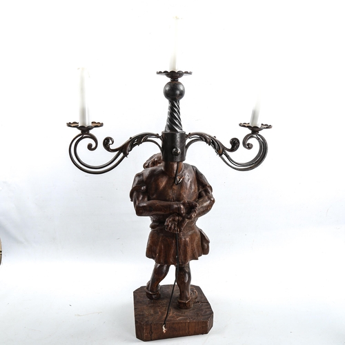 1011 - An unusual wrought-iron 3-branch lamp, supported by a carved wood figure of the Quasimodo, height to... 