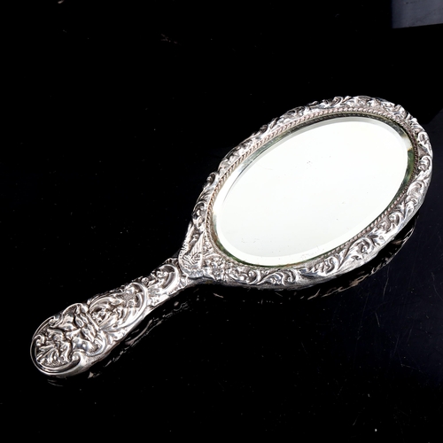 494 - A heavy late Victorian silver dressing table hand mirror, allover relief embossed foliate decoration... 