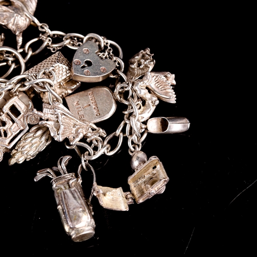 513 - A mid-20th century silver curb link charm bracelet, with heart padlock clasp and 19 charms, bracelet... 