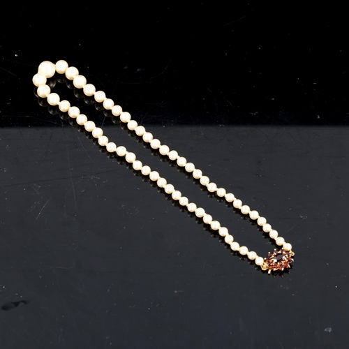 593 - A Vintage graduated single-row pearl necklace, with garnet set 9ct gold clasp, hallmarks London 1985... 