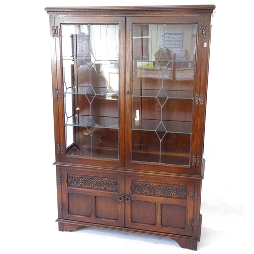 2082 - An oak bookcase with 2 leadlight glazed doors, and carved panelled cupboards under, W108cm, H161cm, ... 