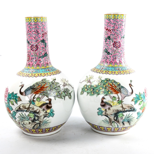 106 - A pair of Chinese porcelain narrow-neck bottle vases, decorated with peacocks and prunus and panels ... 