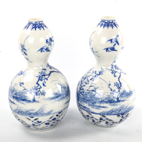 77 - A pair of Japanese blue and white porcelain double-gourd vases, with hand painted decoration and ret... 