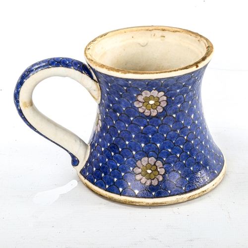 84 - A Turkish pottery mug, with painted flowers on blue scale ground, height 11cm