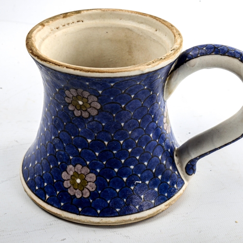 84 - A Turkish pottery mug, with painted flowers on blue scale ground, height 11cm