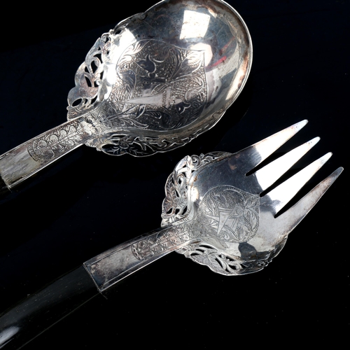 531 - A pair of Middle Eastern unmarked silver horn-handled salad servers, pierced and engraved floral dec... 