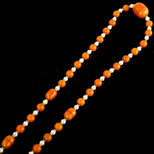 590 - A single-row amber bead and pearl sautoir necklace, with unmarked yellow metal spacers and carved am... 