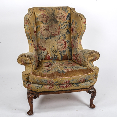 288 - A Georgian wingback armchair, with out-scrolled arms and needlepoint upholstery, raised on carved wa... 