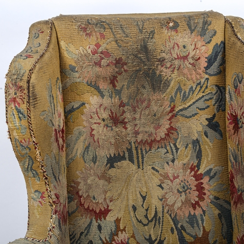 288 - A Georgian wingback armchair, with out-scrolled arms and needlepoint upholstery, raised on carved wa... 