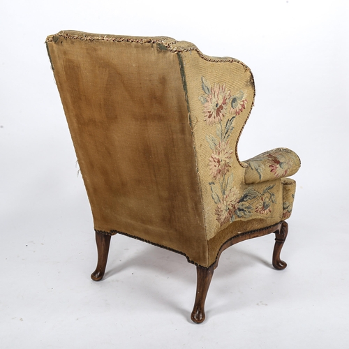 288 - A Georgian wingback armchair, with out-scrolled arms and needlepoint upholstery, raised on carved wa... 