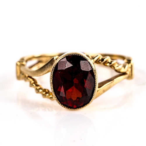 621 - A late 20th century unmarked gold garnet dress ring, set with oval mixed-cut garnet with rope twist ... 