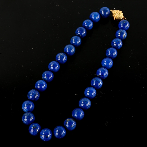 643 - A large single-row polished lapis lazuli bead necklace, with unmarked yellow metal clasp, bead diame... 