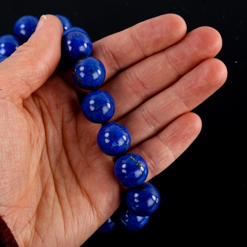 643 - A large single-row polished lapis lazuli bead necklace, with unmarked yellow metal clasp, bead diame... 