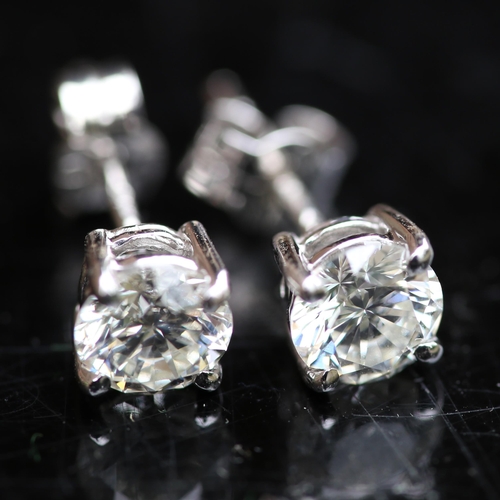 679 - A pair of modern 1.2ct solitaire diamond stud earrings, in 18ct white gold settings with modern roun... 