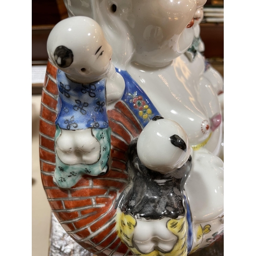 136 - A Chinese porcelain seated Buddha with children, height 26cm, impress mark under base