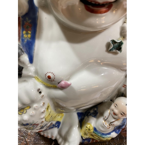 136 - A Chinese porcelain seated Buddha with children, height 26cm, impress mark under base