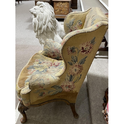 288 - A Georgian wingback armchair, with out-scrolled arms and needlepoint upholstery, raised on carved wa... 