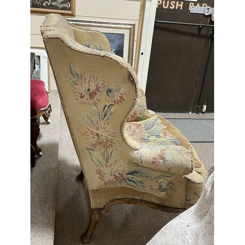 288 - A Georgian wingback armchair, with out-scrolled arms and needlepoint upholstery, raised on carved wa... 