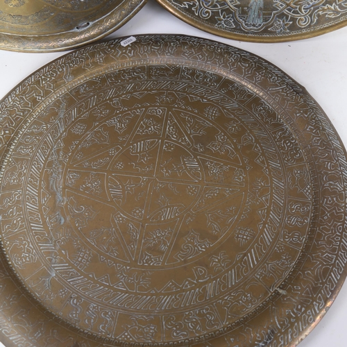 617 - An Eastern brass tray/table-top with engraved decoration, 50cm, and 2 similar smaller trays