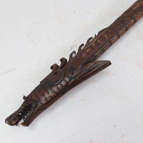 1035 - An Oriental carved wood blowpipe, length 86cm