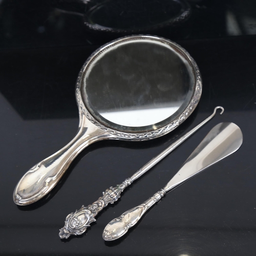 1256 - A silver-backed dressing table mirror, a silver-handled button hook, and glove stretcher (3)