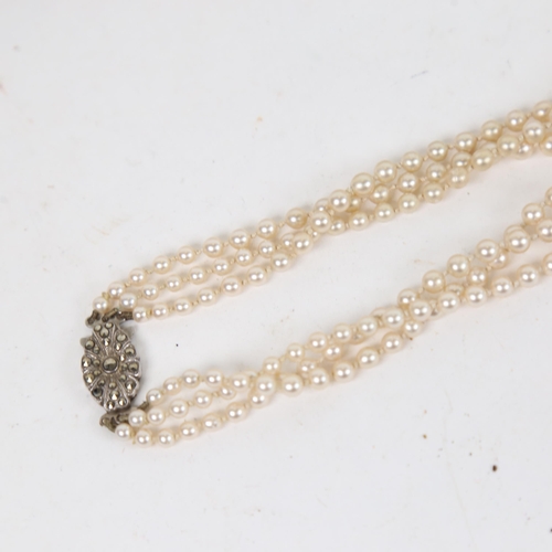 1303 - A triple-strand imitation pearl necklace, with a sterling silver and marcasite set clasp