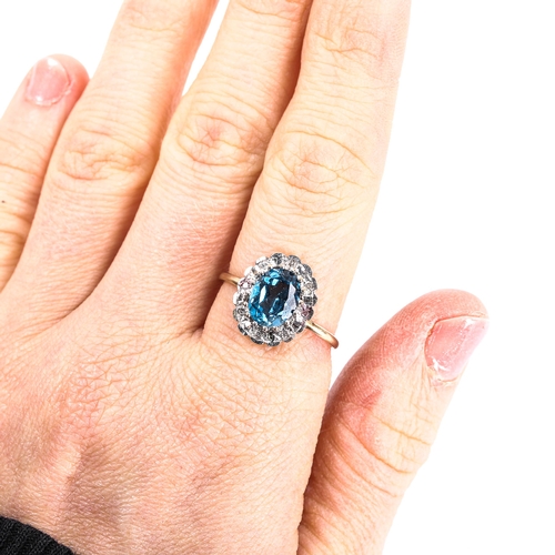 106 - A modern blue topaz and diamond cluster ring, unmarked gold settings with oval mixed-cut topaz and s... 