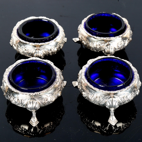 130 - A set of 4 Edwardian silver salt cellars, relief embossed floral decoration with blue glass liners, ... 