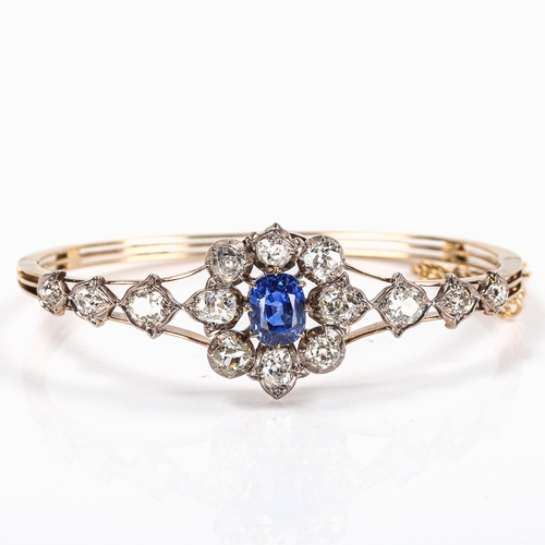 51 - A fine sapphire and diamond cluster hinged bangle, set with central oval mixed-cut blue sapphire, ap... 